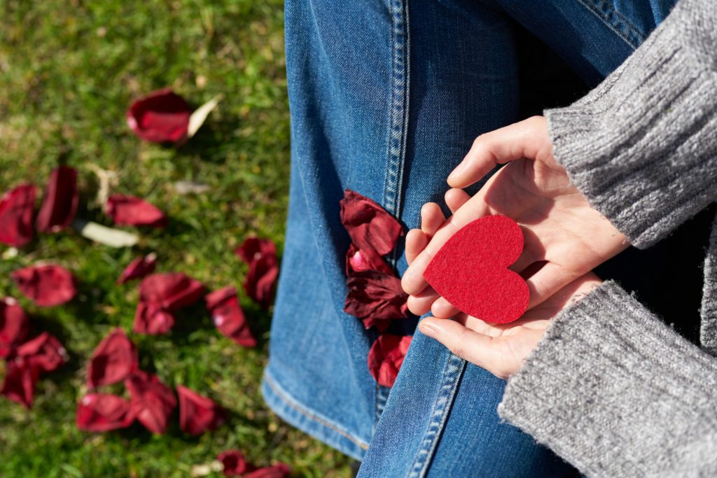 femme tenant un coeur rouge dans les mains pour symboliser le pardon